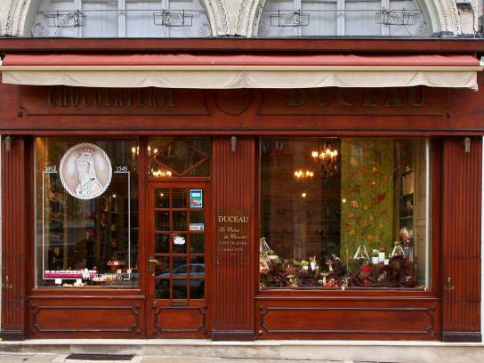 Chocolaterie Duceau : la devanture sur rue en bois verni, ornée de cannelures sur les montants de la vitrine et de moulures sur le linteau et le soubassement - Angoulême, Charente, Nouvelle-Aquitaine, France.