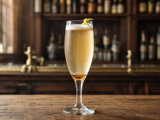 Cocktail Pineau Royal au champagne et zeste de citron dans une flute sur table en bois de bar chic.